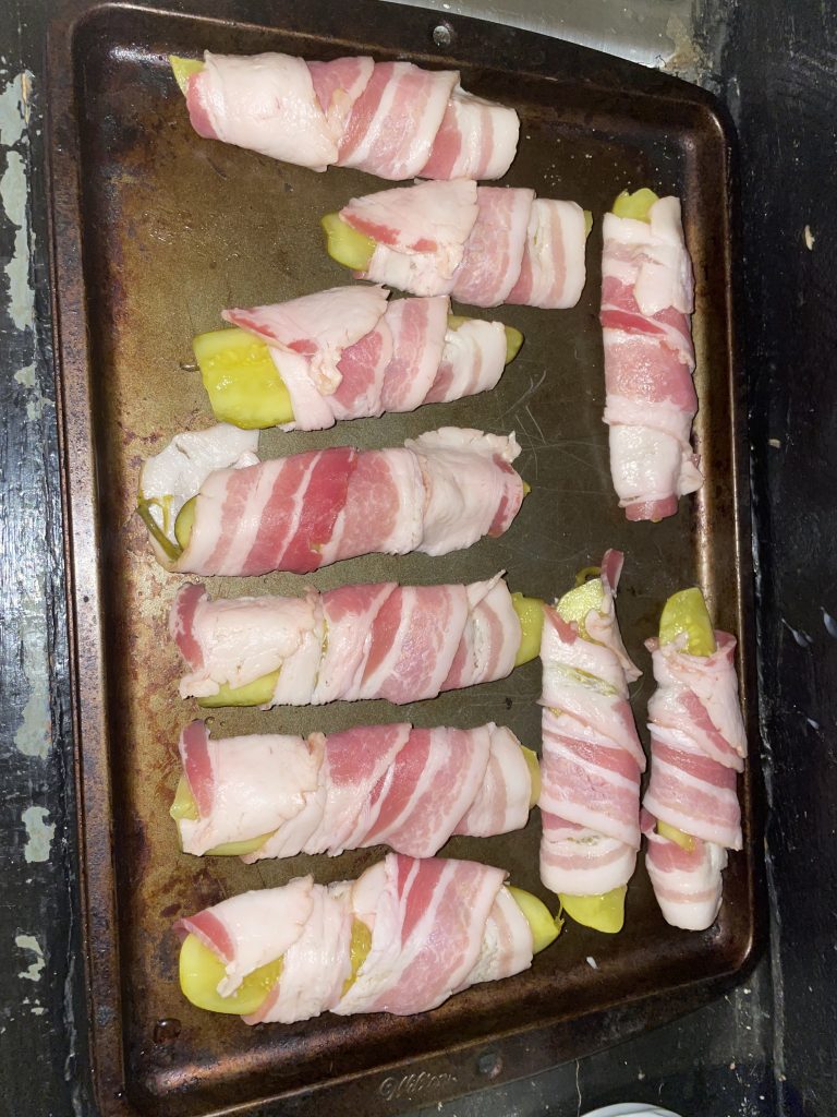 Bacon Wrapped Dill pickles on tray uncooked.